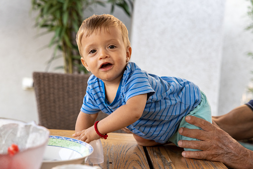 Portrait of curious Caucasian toddler boy crawling on the desk