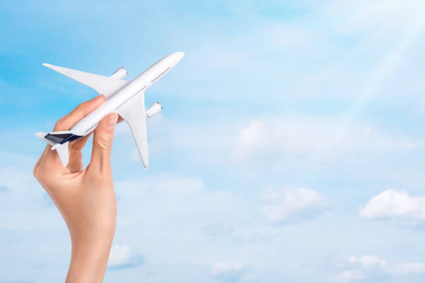 istock Hand holding airplane over blue sky background. 1389688872