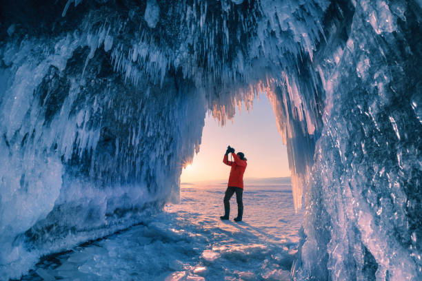 l'uomo turista fotografa la grotta di ghiaccio sul lago baikal - lake baikal lake landscape winter foto e immagini stock