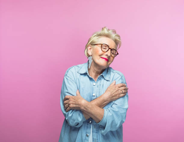Elderly woman hugging self with eyes closed