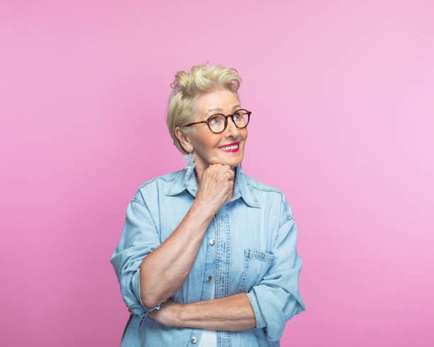 Thoughtful senior woman with hand on chin stock photo