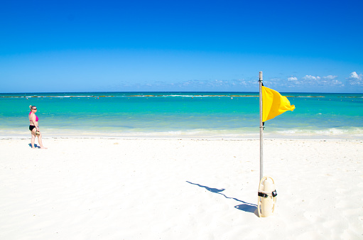 yellow wind warning flag on a caribbean beach in mexico