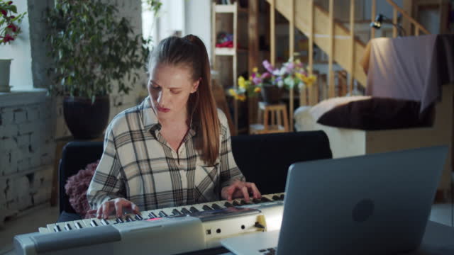 A woman communicates with a music teacher through a laptop. He teaches her to play the piano