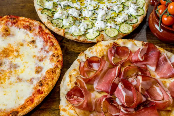 Photo of A delicious trio of Italian pizzas with Margherita, Zucchini with Stracchino and Speck with Mozzarella
