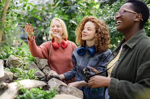 Diverse group of friends enjoying themselves while visiting a local urban greenhouse, smiling and having fun exploring the nature in the middle of the city