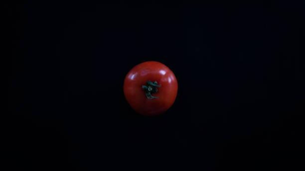 istock Single red tomato, vegetable, isolated on black background, top view 1389698641