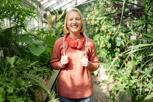 Portrait of a young curious Caucasian woman using her leisure time to enjoy herself while visiting a local greenhouse botanical garden, smiling and exploring nature in the middle of the city