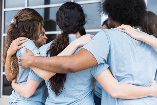 istock Diverse group stands with arms around each other 1389699623
