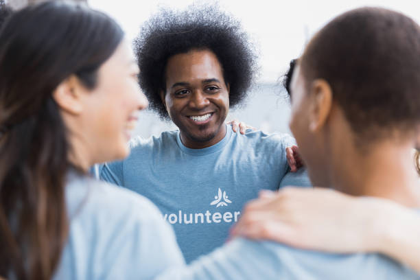 istock Diverse group stands in circle with arms on shoulders 1389700018