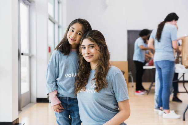 istock Two sisters pose for photo as volunteers work in background 1389700963