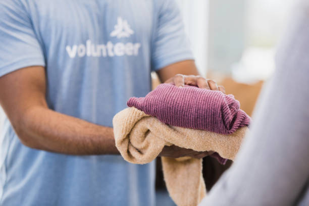 Unrecognizeable person hands clothing items to someone