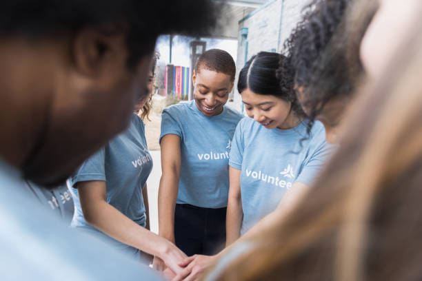 istock Diverse group stands with hands together to pray 1389702361
