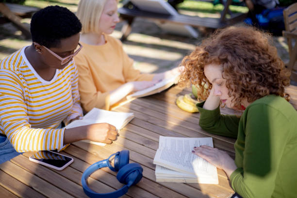 vue à angle élevé d’un groupe diversifié d’étudiantes ayant un club de lecture ensemble à l’extérieur - club détudiantes photos et images de collection