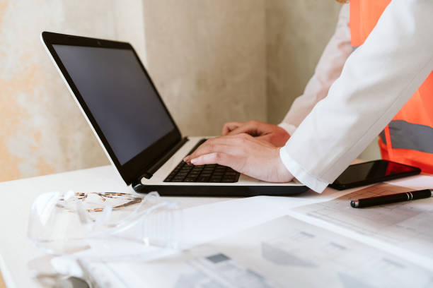 istock unrecognizable architect woman in construction site working on blueprints and laptop 1389702965