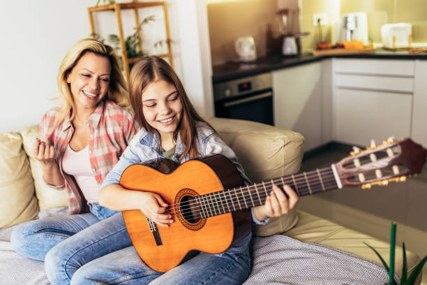 istock Mother and daughter at home playing guitar and singing 1389703030