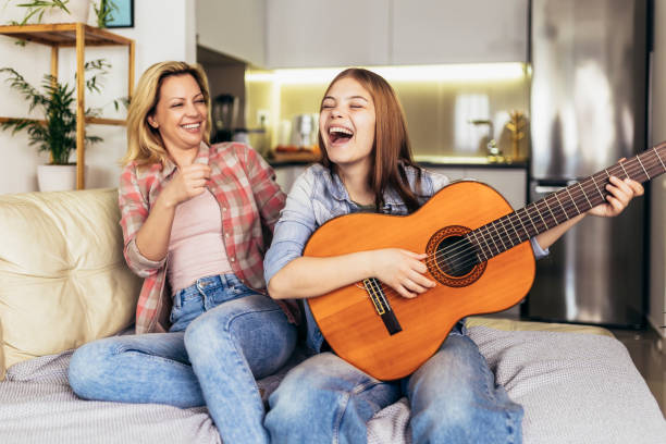 istock Mother and daughter at home playing guitar and singing 1389703032