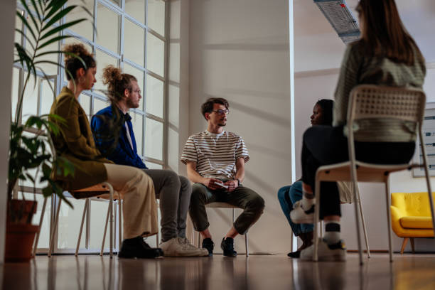 personas amables y diversas que participan en sesión de terapia de grupo - desintoxicación fotografías e imágenes de stock