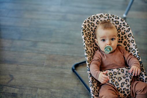 Cute baby boy sucking on a pacifier looking up