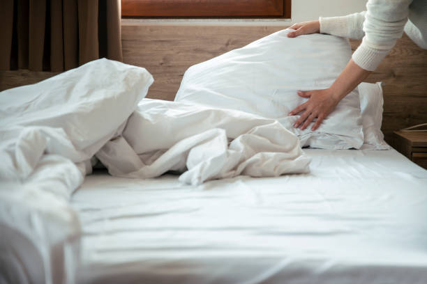 Female makes the bed in the bedroom Daily housekeeping service. Maid Cleaning messy hotel bed cushion and duvet, changing bed sheets with clean. Selective focus. Copy space bed sheets stock pictures, royalty-free photos & images