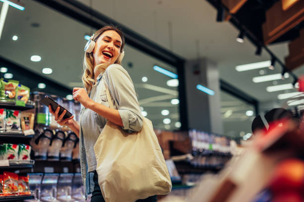 Joyful woman with earphones listening to the music in a supermarket stock photo
