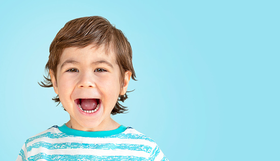 portrait of smiling little boy on blue background close up