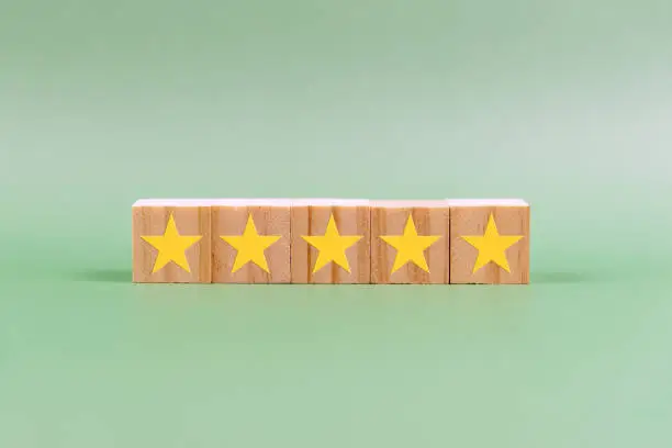 Photo of 5 star rating on wood block on green background
