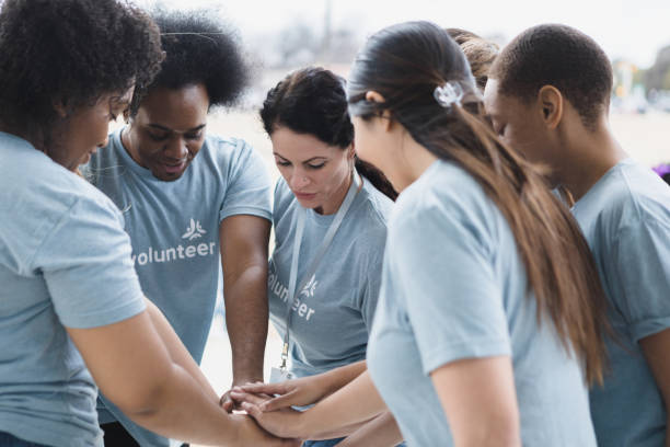 istock Volunteers stand with hands stacked 1389710177