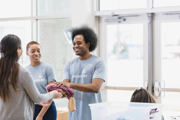 istock Young man gives clothing items away 1389710183