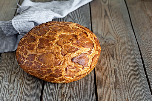 Fresh crispy Tiger (Dutch) bread with a delicious beautiful crust and wonderful homemade taste on a rustic wooden background. Bakery product with cracks.