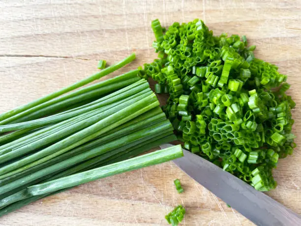 close-up of chopped chives on wooden cutting board