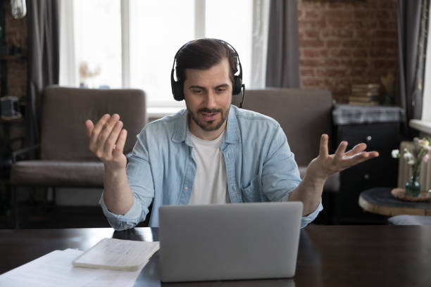 istock Positive busy millennial freelance employee man speaking at webcam 1389712989