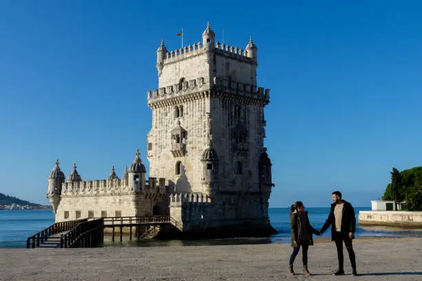 Photo of Woman and man next to the Belem Tower in Lisbon, Portugal.