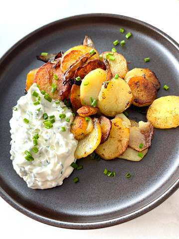close-up of a plate with roasted potatoes and curd with chives
