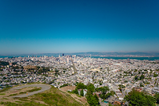 View of San Francisco and the Bay Area from Twin Peaks park on a clear, blue sky sunny day in Summer, looking out to the bay with the city skyline and the Bay Bridge in the distance