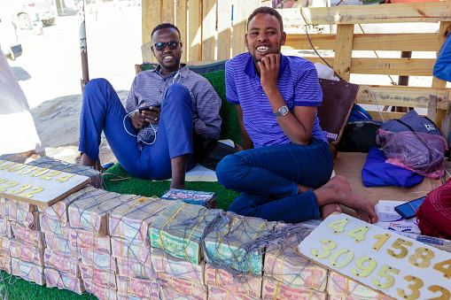 Hargeysa, Somaliland - November 10, 2019: Money Sellers with the selling Meshes of Colorful Money on the Street