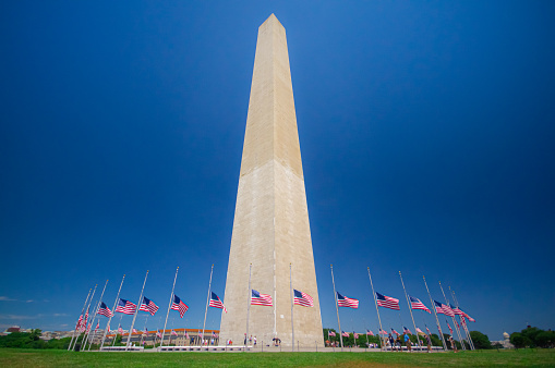 Washington Monument in Washington DC on a clear blue sky day with flags at half mast