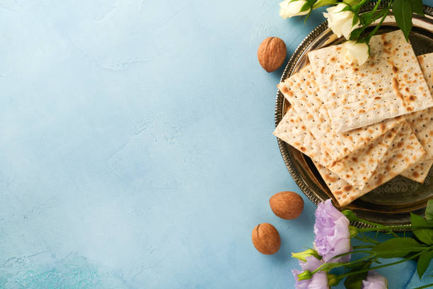istock Passover celebration concept. Matzah, red kosher walnut and spring beautiful rose flowers. Traditional ritual Jewish bread on light turquoise or blue background. Passover food. Pesach Jewish holiday. 1389717985