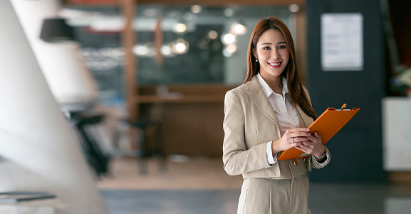 Smiling young businesswoman looking at camera while standing in the co working space.