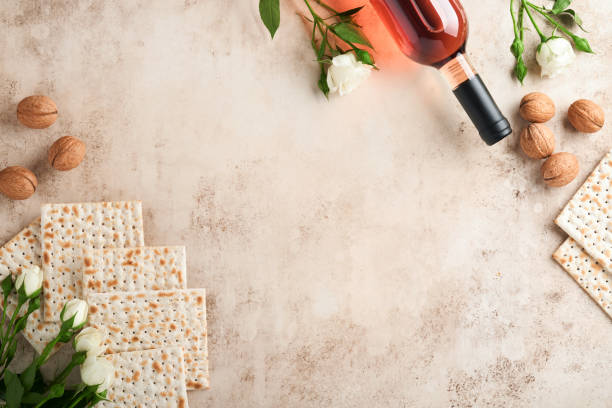 過越祭のお祝いのコンセプト。マッツァー、赤いコーシャクルミ、春の美しいバラの花。砂の上の伝統的な儀式のユダヤ人のパンは、古いコンクリートの背景を着色します。過越の祭の食物� - matzo judaism traditional culture food ストックフォトと画像