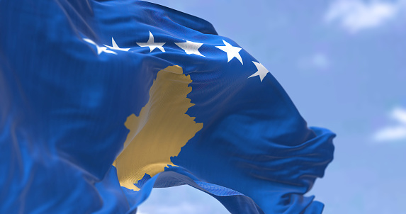Detail of the national flag of Kosovo waving in the wind on a clear day. Kosovo is a partially recognized state in Southeast Europe. Selective focus.
