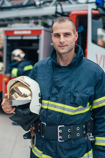 Firefighter with work helmet under arm looking at camera