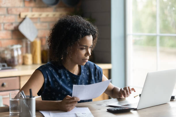 Serious millennial African American woman calculating taxes stock photo