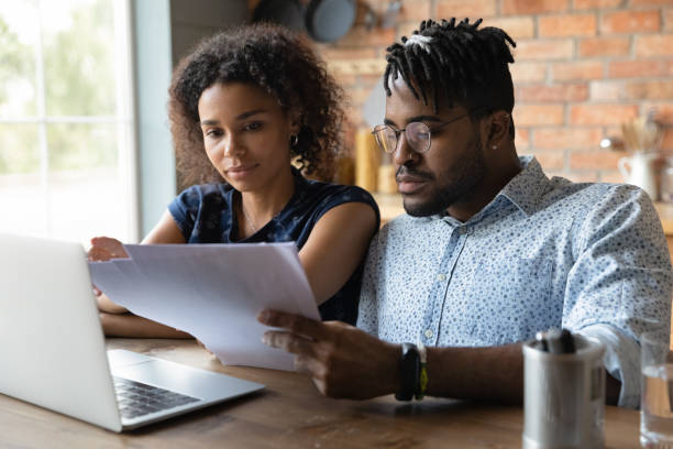 istock Serious millennial black married couple reading documents at laptop together 1389726943