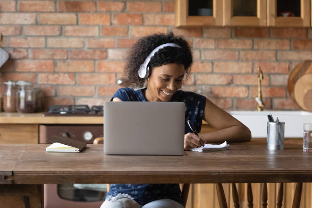 istock Happy Black student girl in wireless headphones writing notes 1389727730