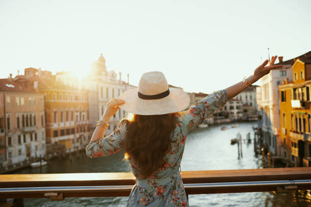 Seen from behind modern woman in floral dress with hat stock photo