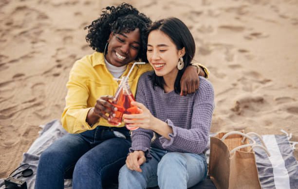 istock Two friends sitting on the beach having fun and drinking on the spring day 1389733525