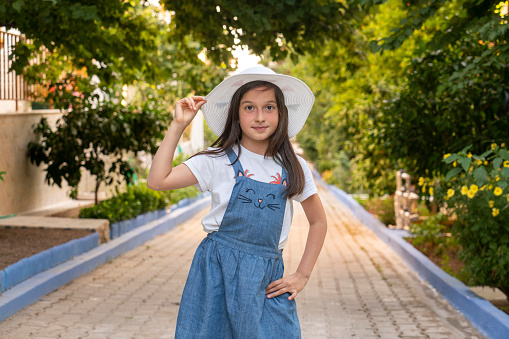 Portrait of clever funny small girl hand touch mortarboard hat demonstrate thumb up isolated on orange color background.