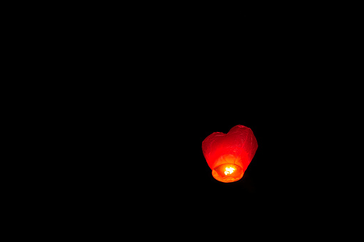 Low angle view of illuminated heart shaped Chinese lantern flying against dark sky at night in wedding party