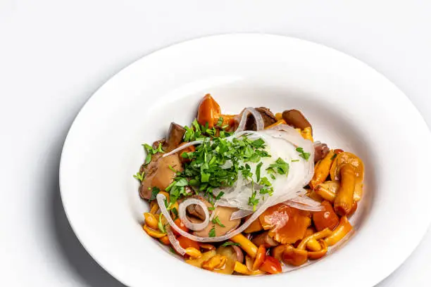 Photo of Pickled forest mushrooms with onions and parsley are on a plate