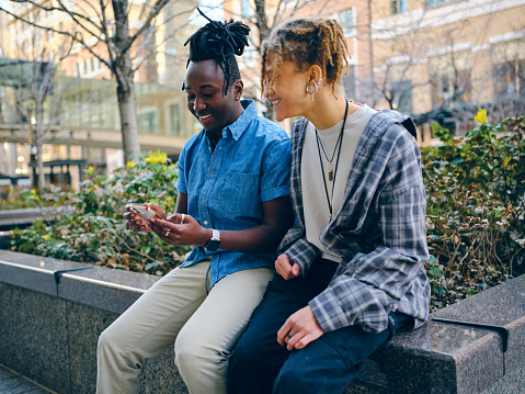 Two young people hanging out together in the downtown area of a city.